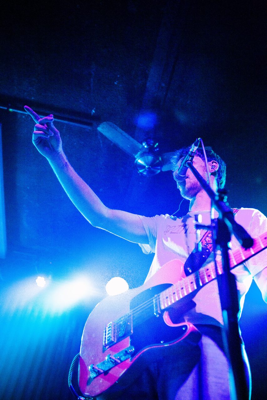 Singer and guitarist pointing to the crowd in blue light