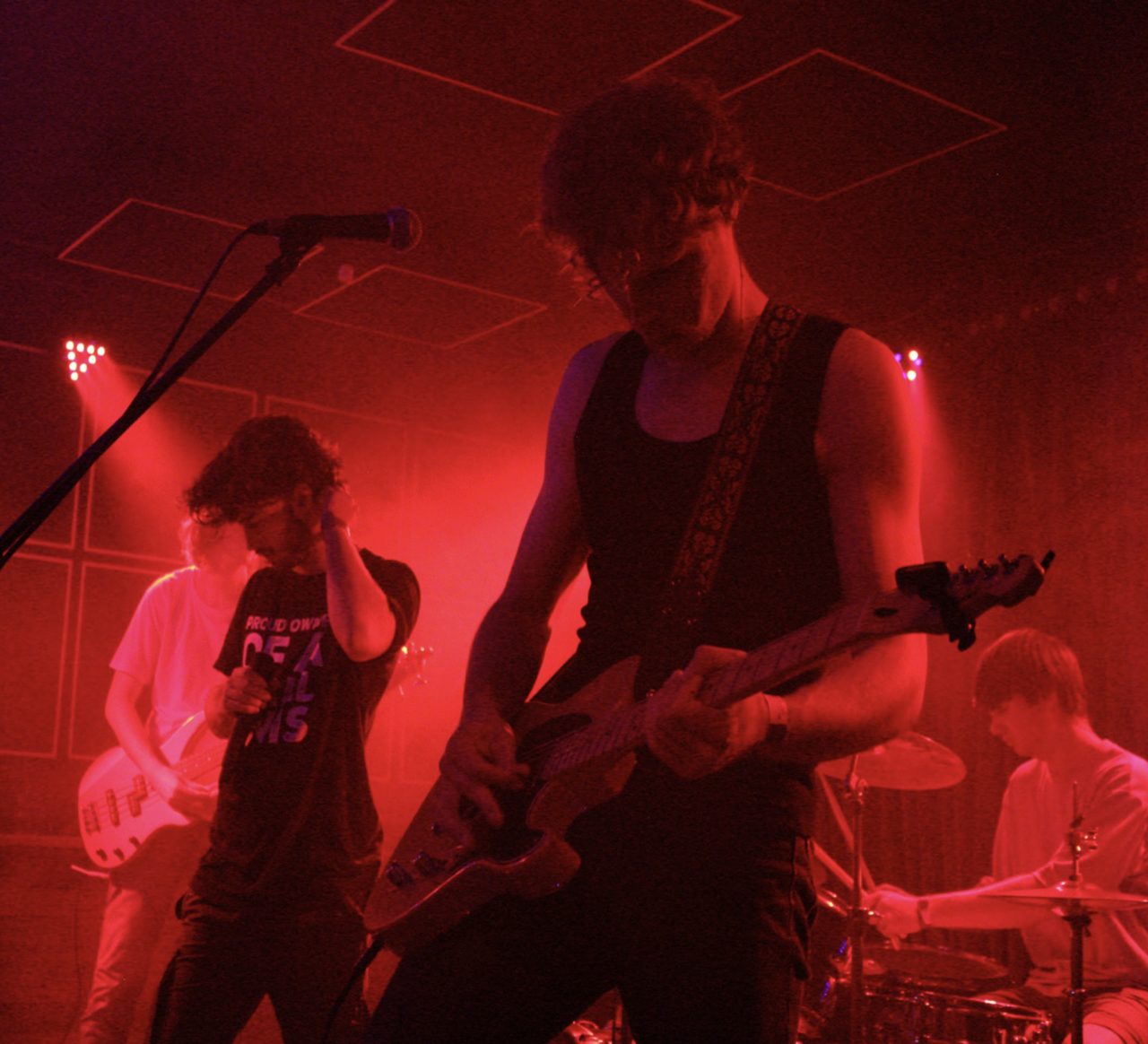 The full band playing under deep red light